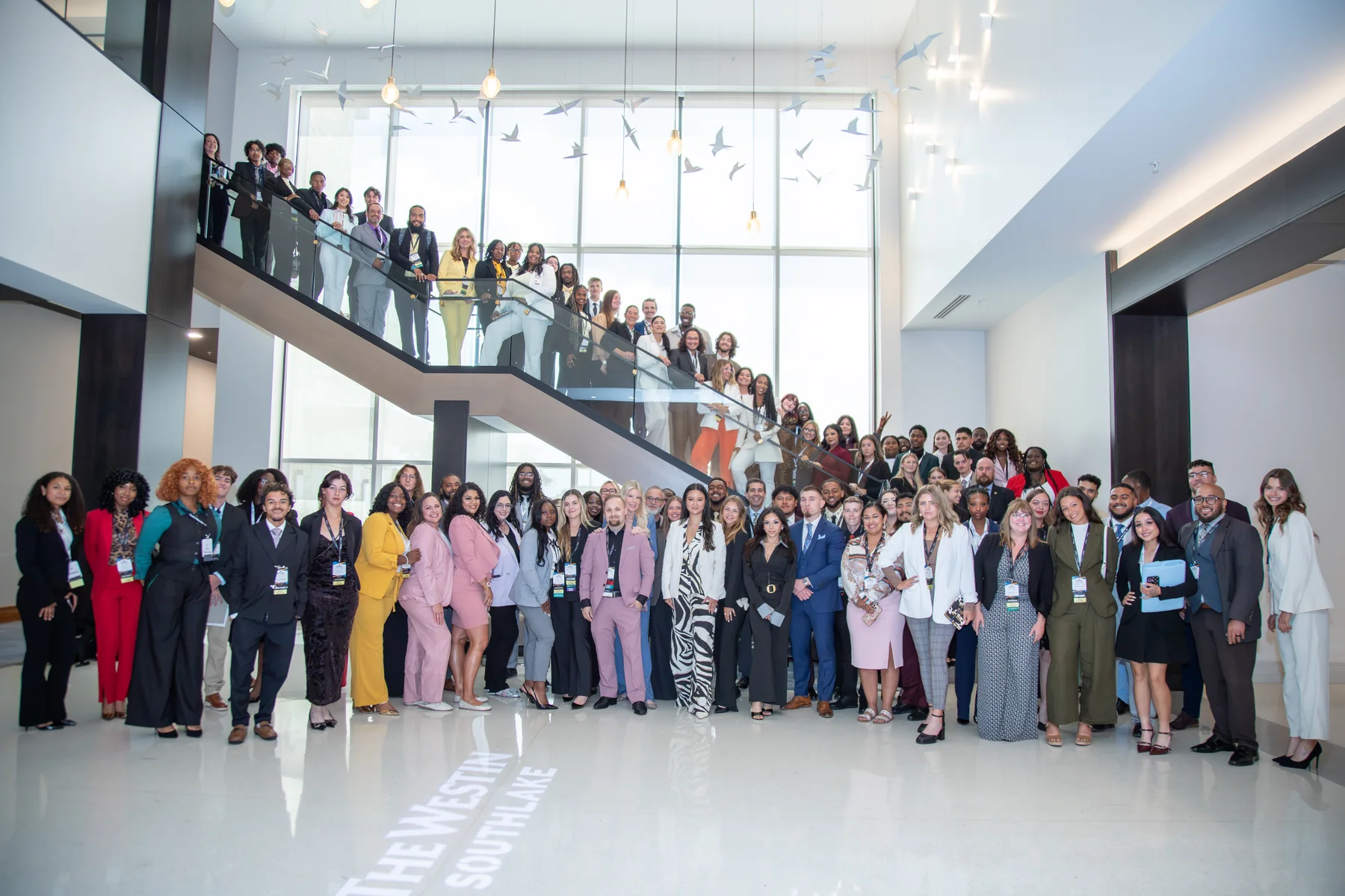 Universal Events Mastery Summit attendees gathered on the atrium staircase at the host hotel